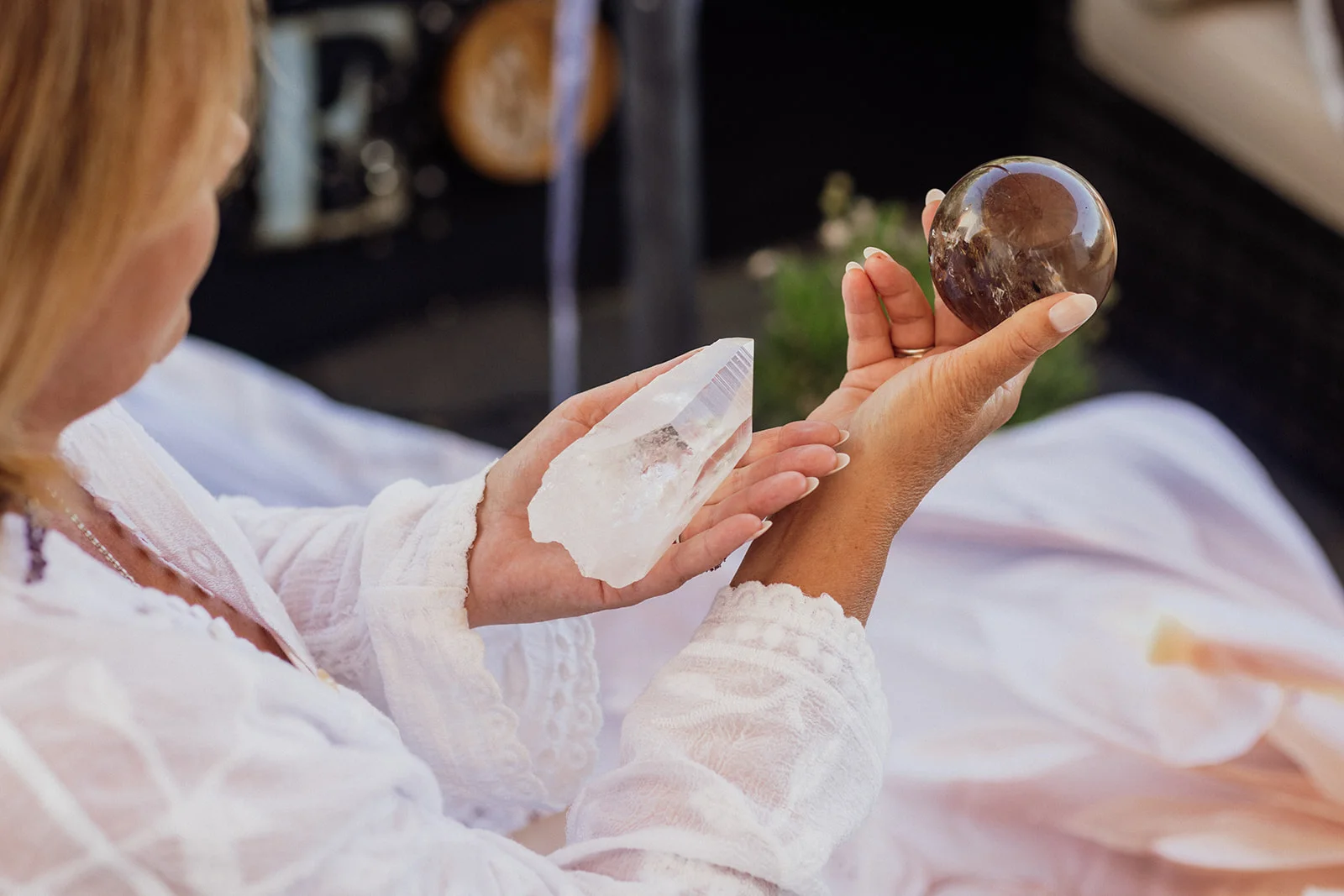 Two hands and a row of coloured healing crystals connected by ribbons of light